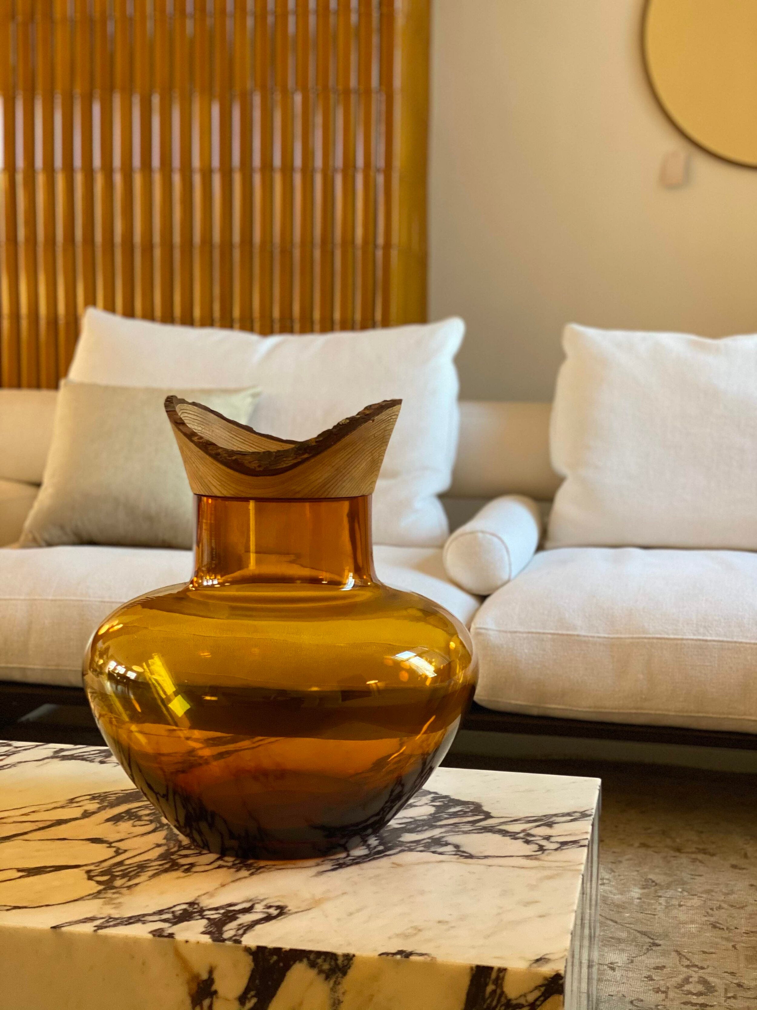 Big Bloom Stacking Vessel in Amber on table, showcasing a warm, golden hue and an elegant layered design.
