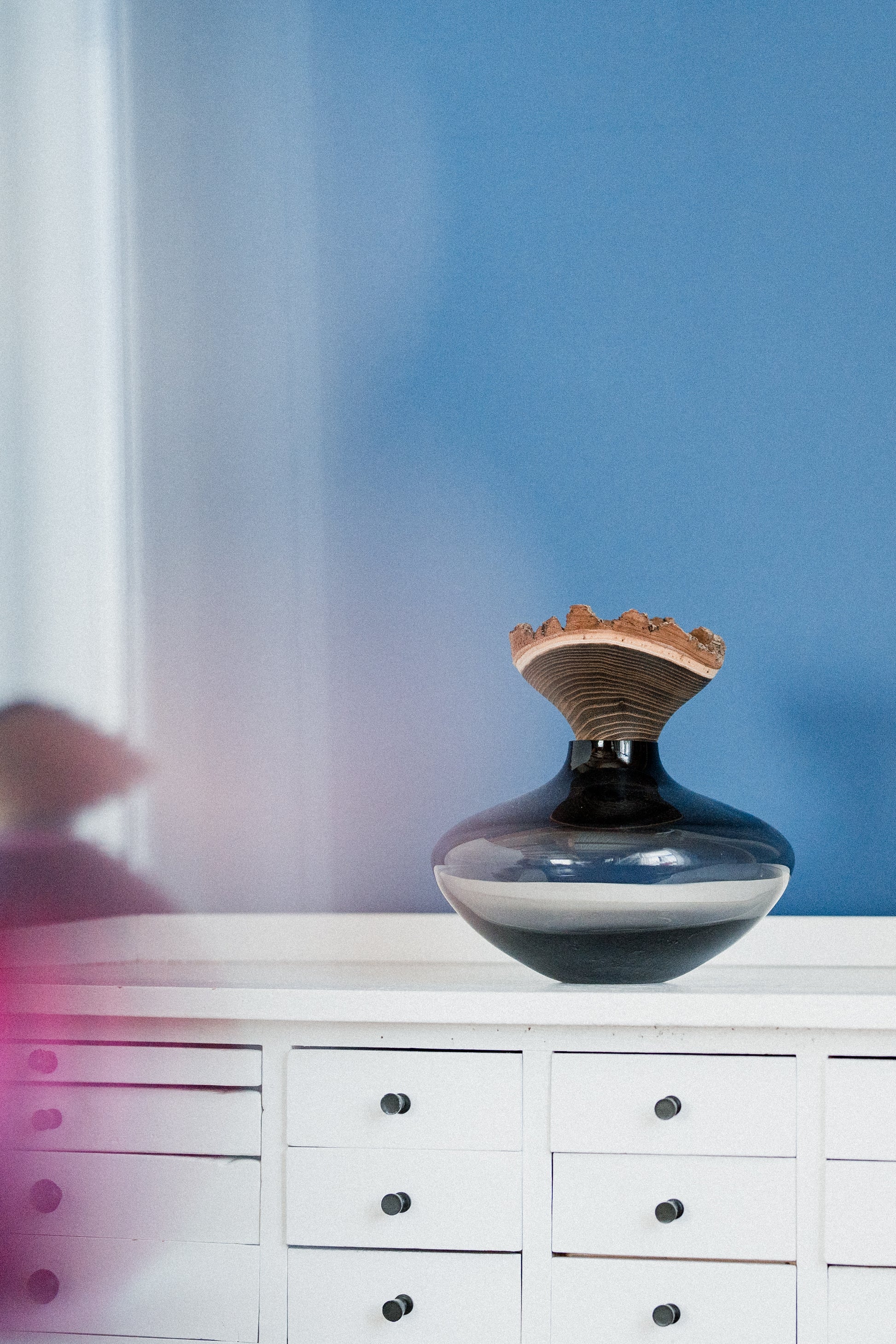 Bloom Stacking Vessel in Smoke on cabinet, showcasing a smooth, sophisticated design with a smoky finish and elegant stacking form.